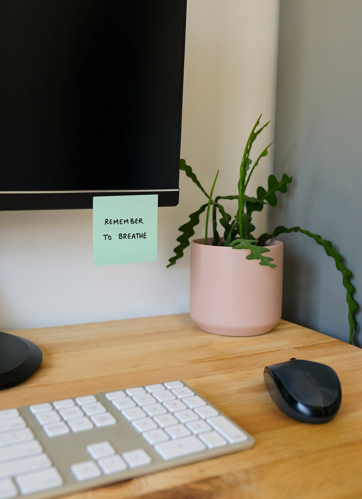 desk with a reminder to breath on the monitor