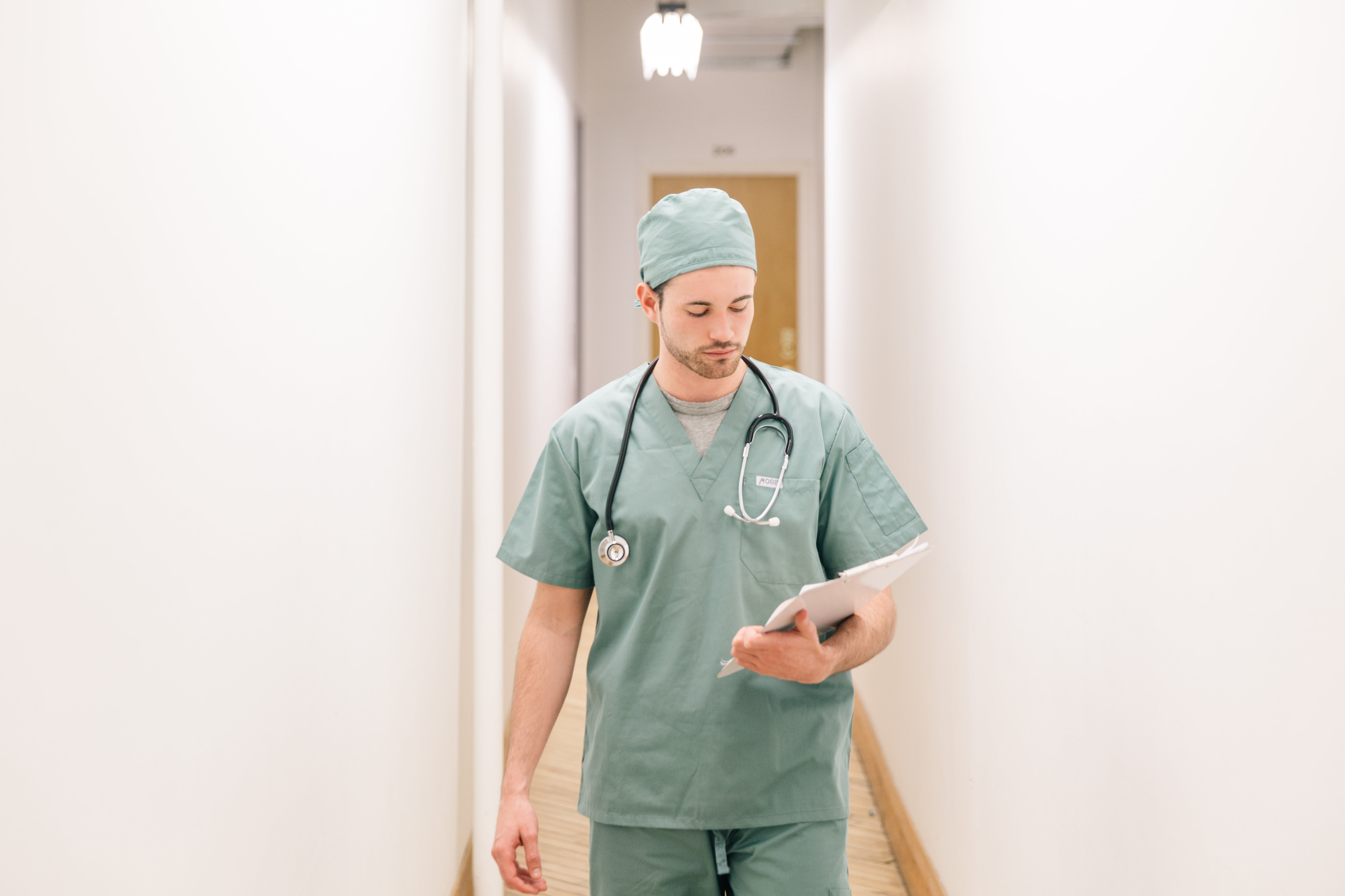 Doctor Walking Down Hallway With Clipboard