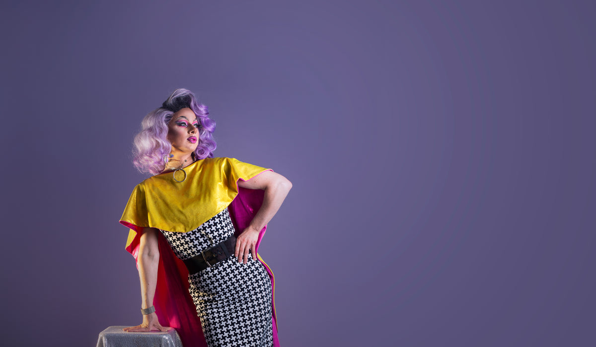 drag queen performer leans on table pose
