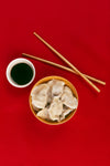 dumplings chopsticks and sauce on a red cloth viewed from above