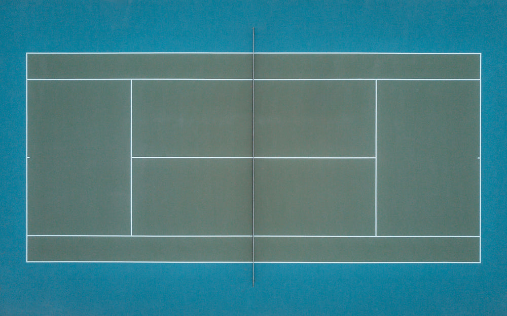 emerald green tennis court as seen from above by a drone