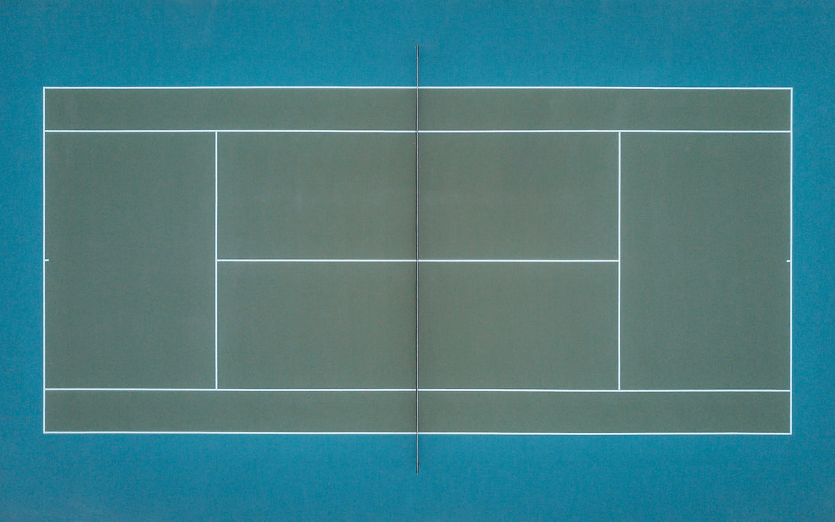 emerald green tennis court as seen from above by a drone
