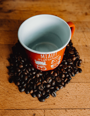 empty cup surrounded by coffee beans