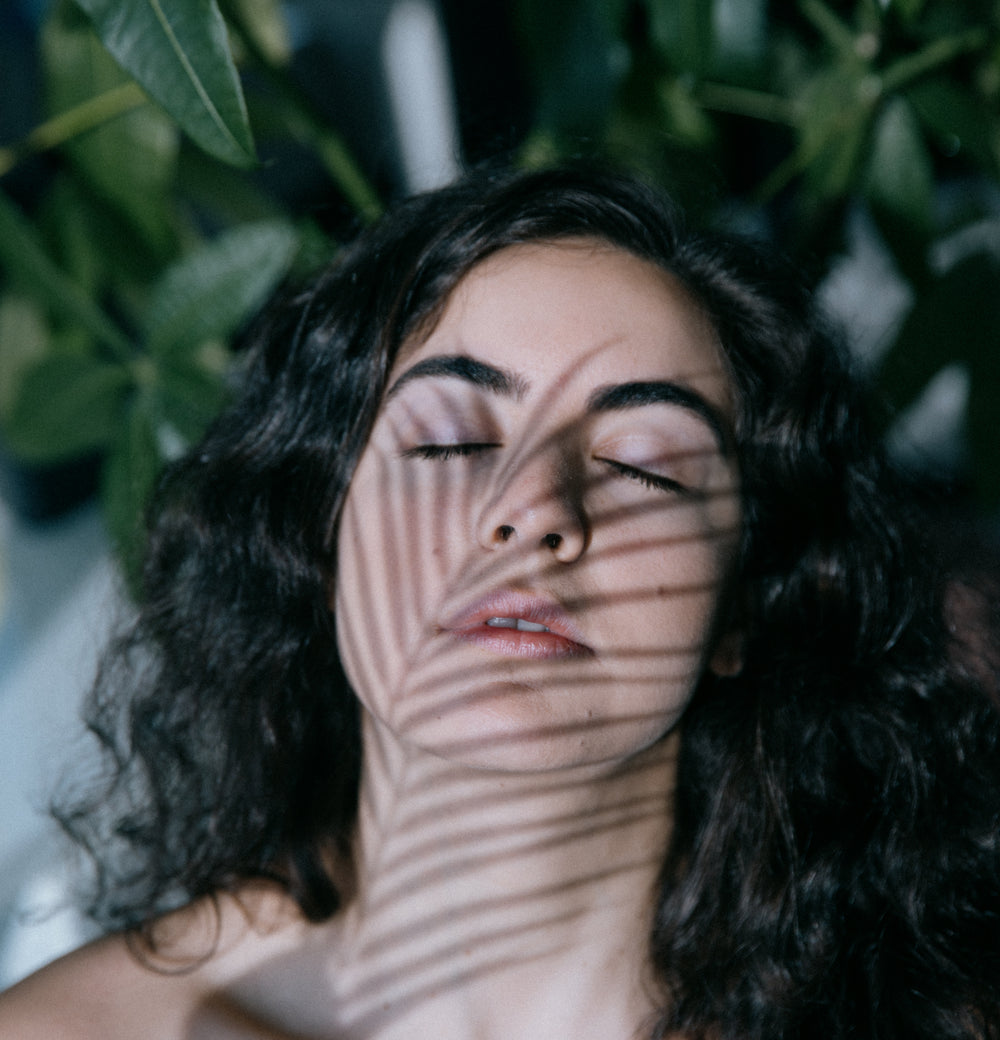 eyes closed while a plant casts a shadow on their face