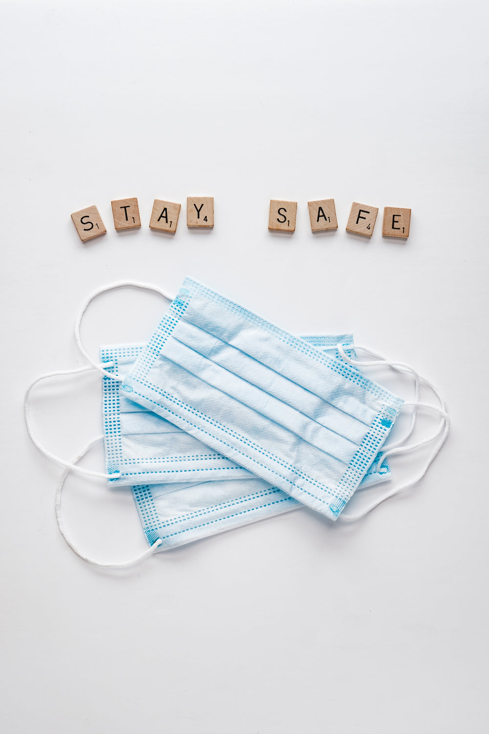 face masks and letter tiles spelling safe hands