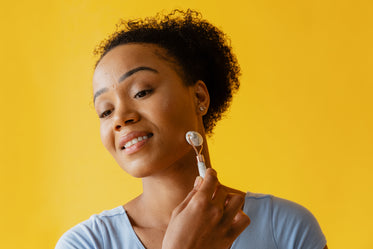 facial roller in use on yellow background