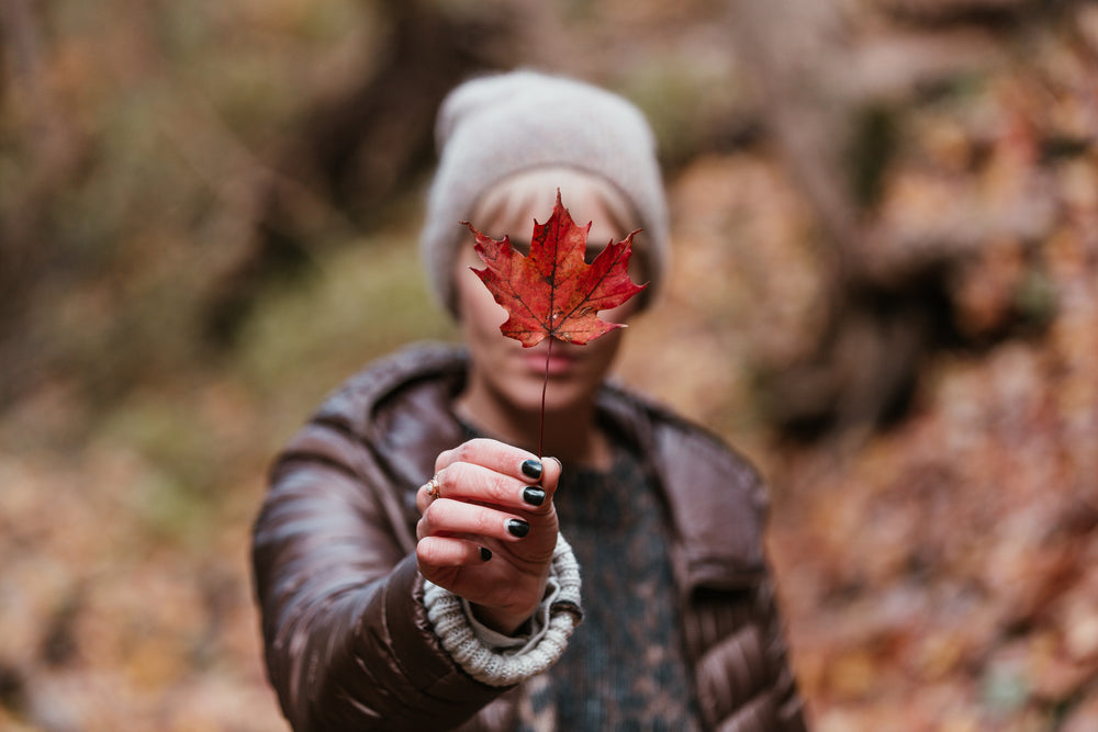 fall fashion holding red autumn leaf