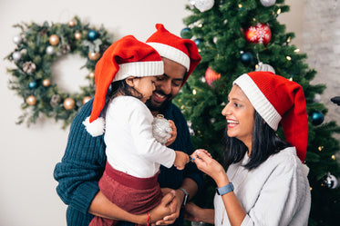 família de três decora a árvore de natal