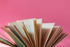 fanned out book pages against a pink background