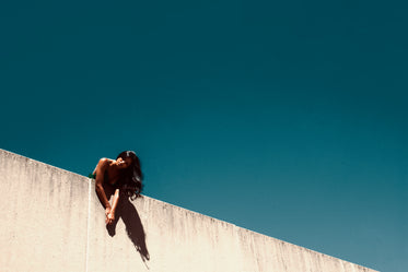 fashion model poses over cement wall and blue sky