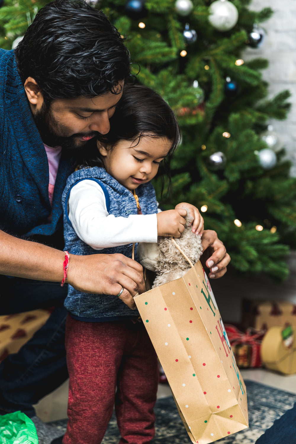 father helps toddler open christmas gifts