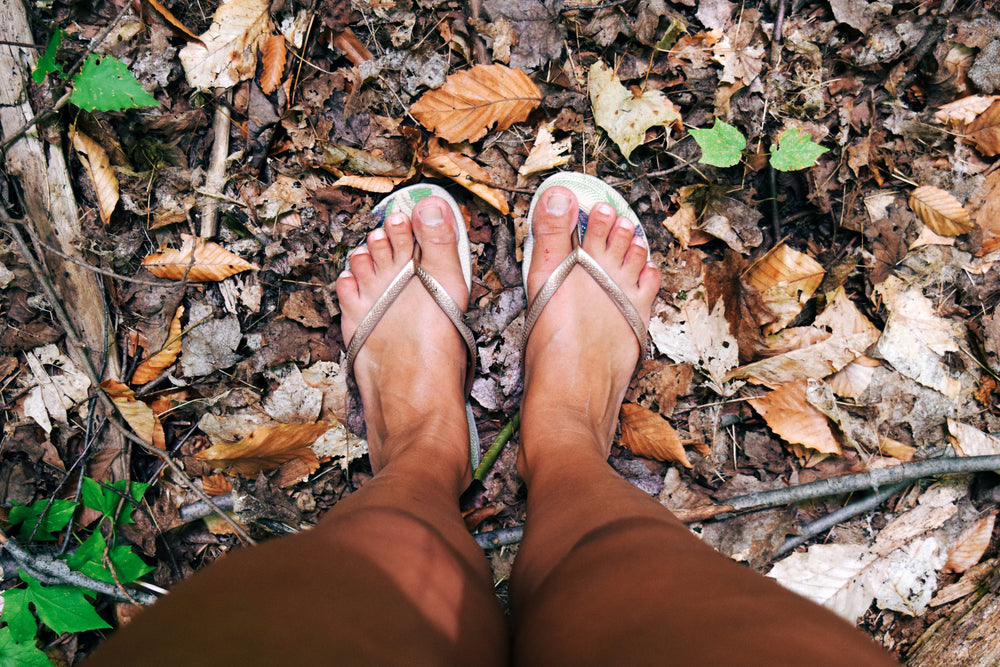 feet in sandals on fall leaves
