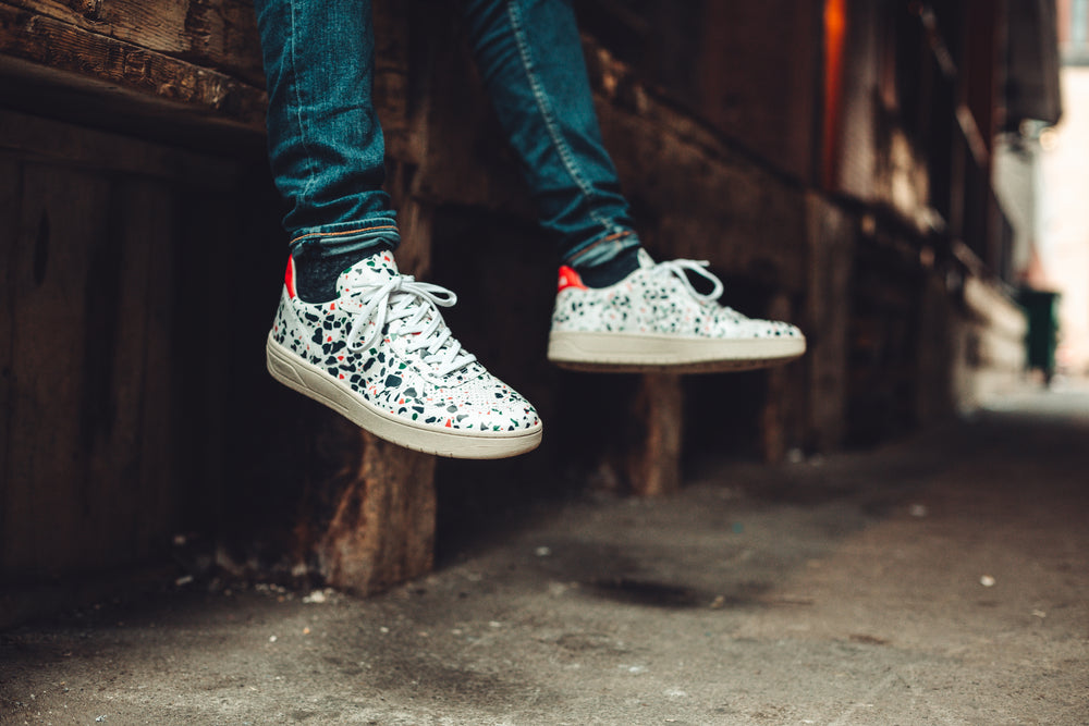 feet wearing white patterned trainers