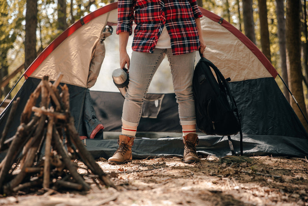 female camper holding supplies in front of tent