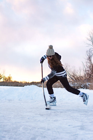 female hockey player practicing stick handling on frozen lake