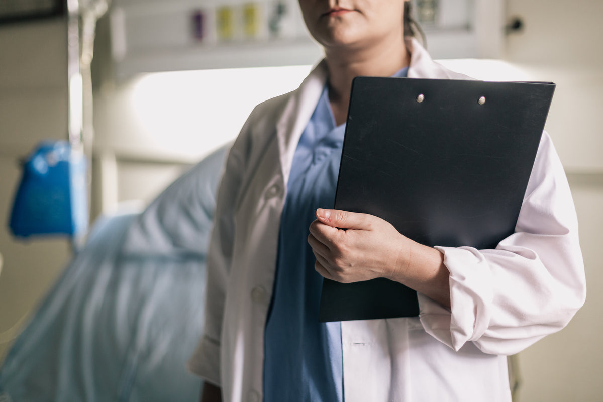 female medical professional holds clipboard in hospital room