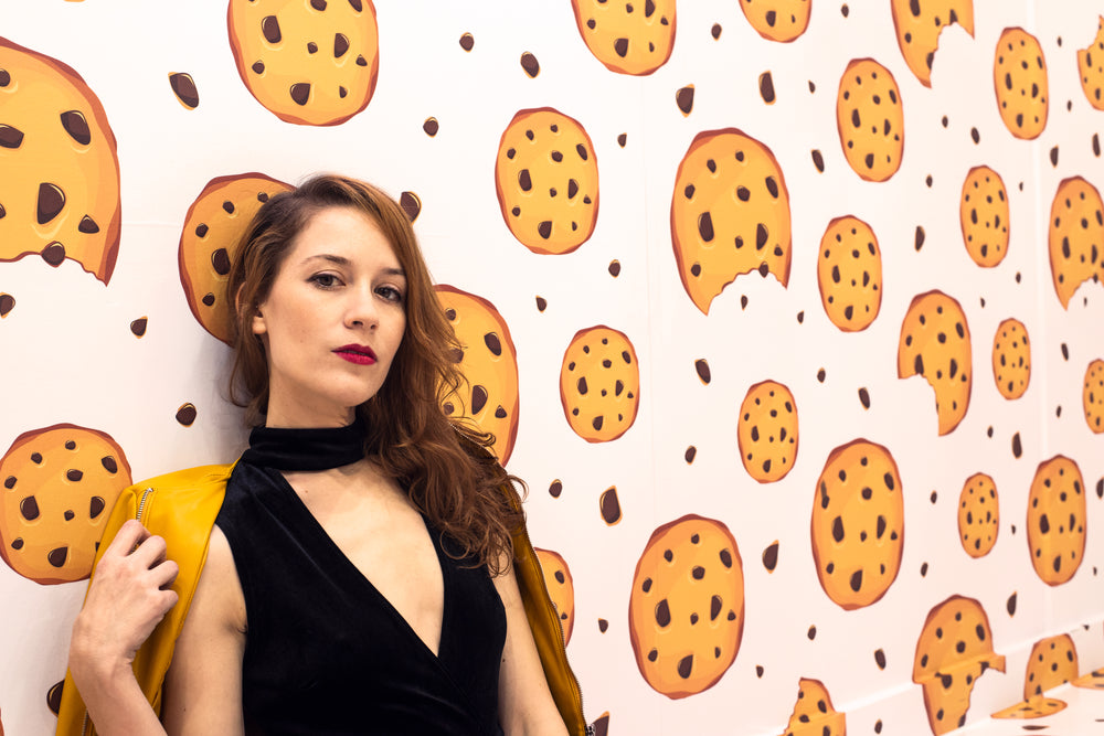 female model leans against a wall covered in cookie wallpaper