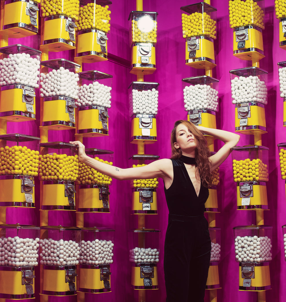female model poses in front of gumball machine covered walls