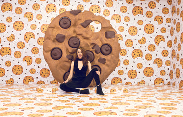 female model poses on floor in front of giant cookie