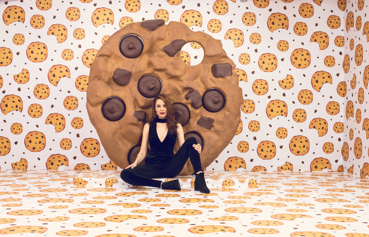 Female Model Poses On Floor In Front Of Giant Cookie