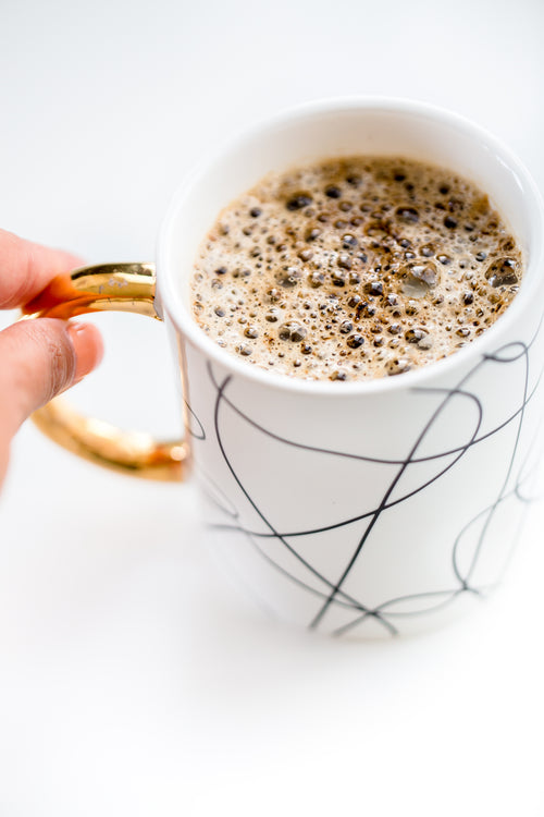 fingers pinch the handle of mug of hot chocolate
