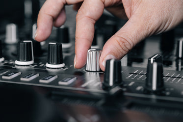 fingers turning dial on dj board