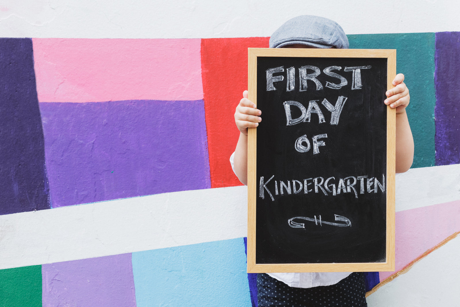 Child holding a first day of kindergarten sign