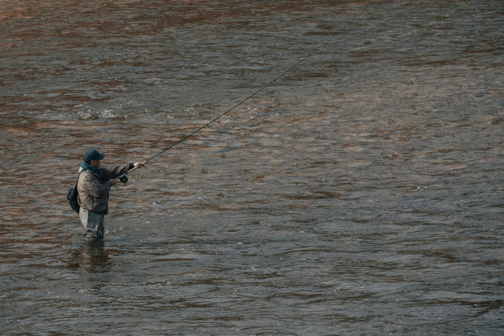 fisherman stands alone in water