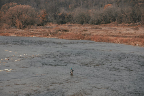 fisherman stands in a large river
