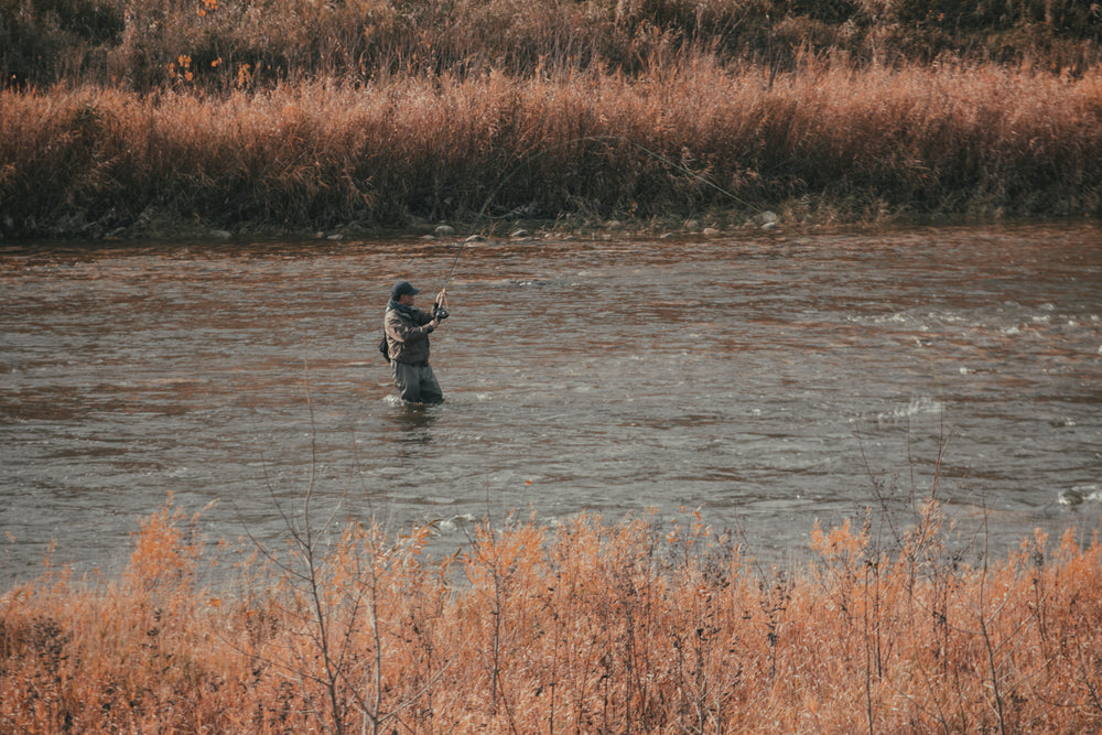 fisherman stands in the rushing river