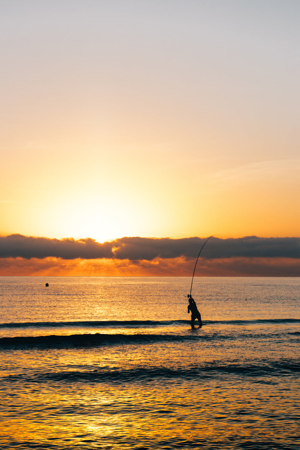 fisherman stands in the water at sunrise