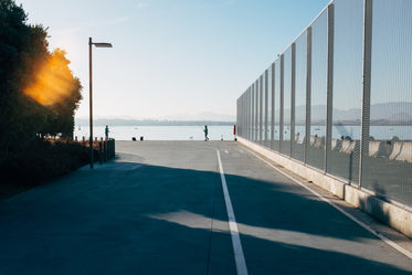 fishermen stand on a concrete dock in the sunset by a bay