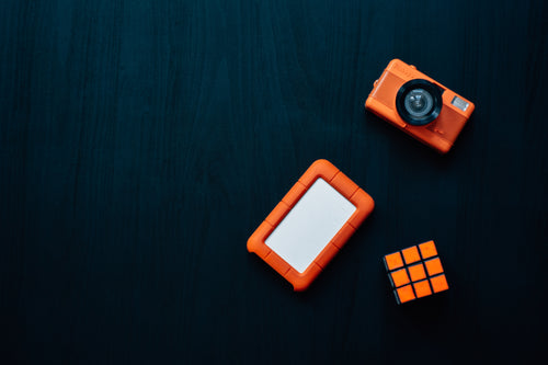 flatlay of a camera rubiks cube and hard drive
