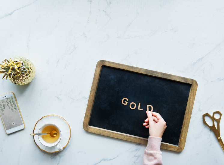 Flatlay Of A Model Spelling "Gold" On A Blackboard