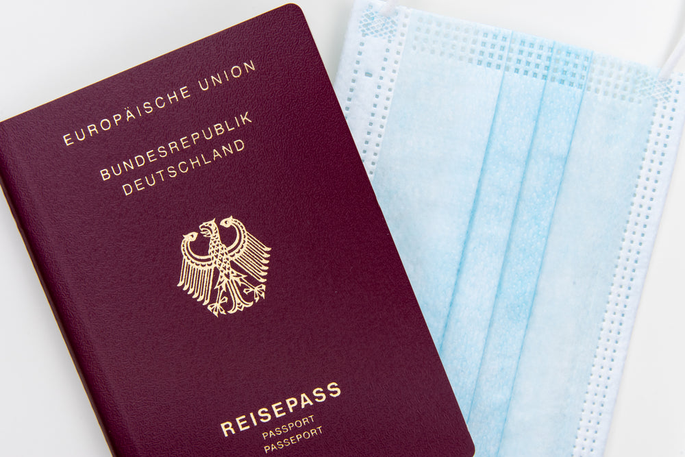 flatlay of a passport and a disposable facemask