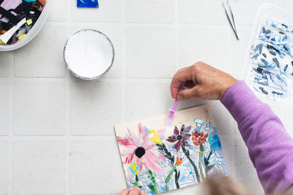 flatlay of a person adding glue to a glass mosaic