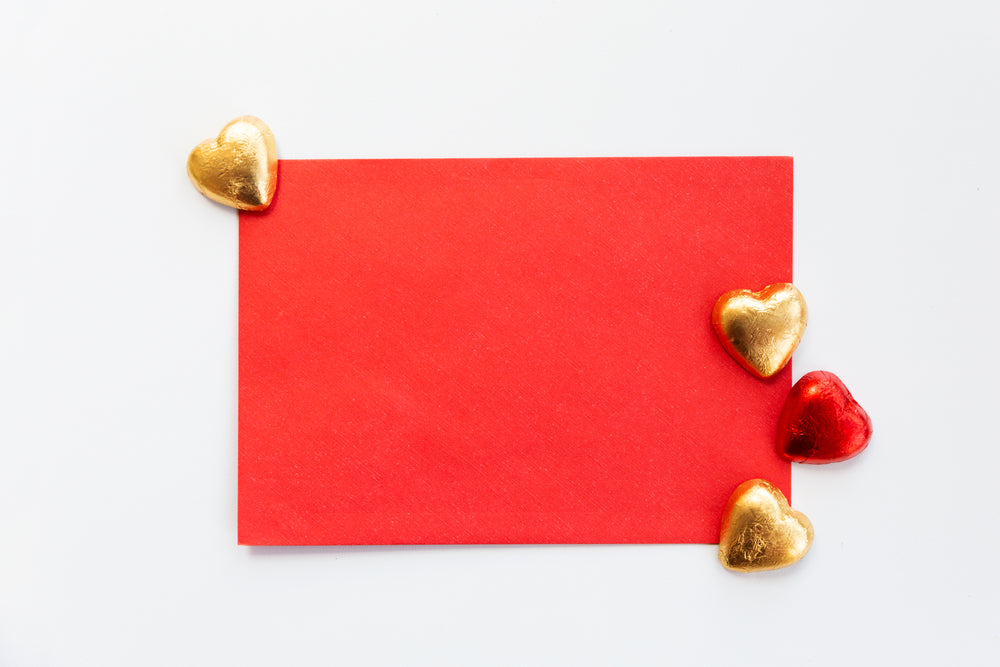 flatlay of a red envelope with gold and red chocolates