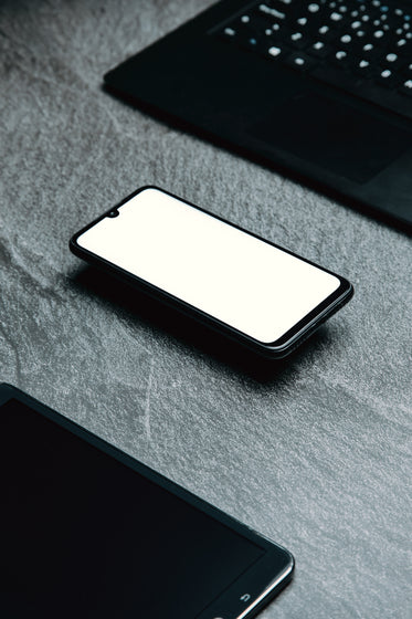 flatlay of a tablet cellphone and laptop keyboard on grey