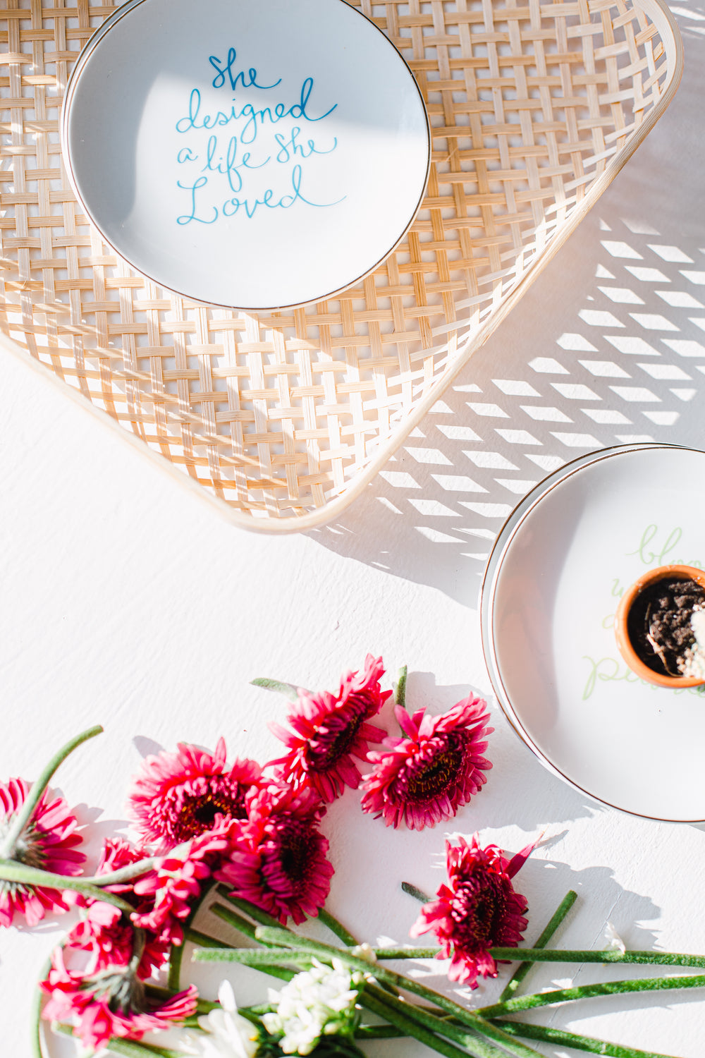 flatlay of a wicker basket next to pink flowers