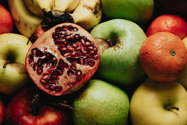 flatlay of half pomegranate and other assorted fruits