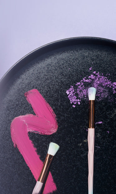 flatlay of makeup brushes and makeup on a black plate