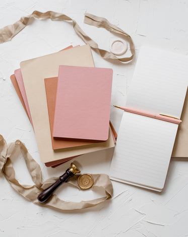 flatlay of notebooks a ribbon and a wax seal