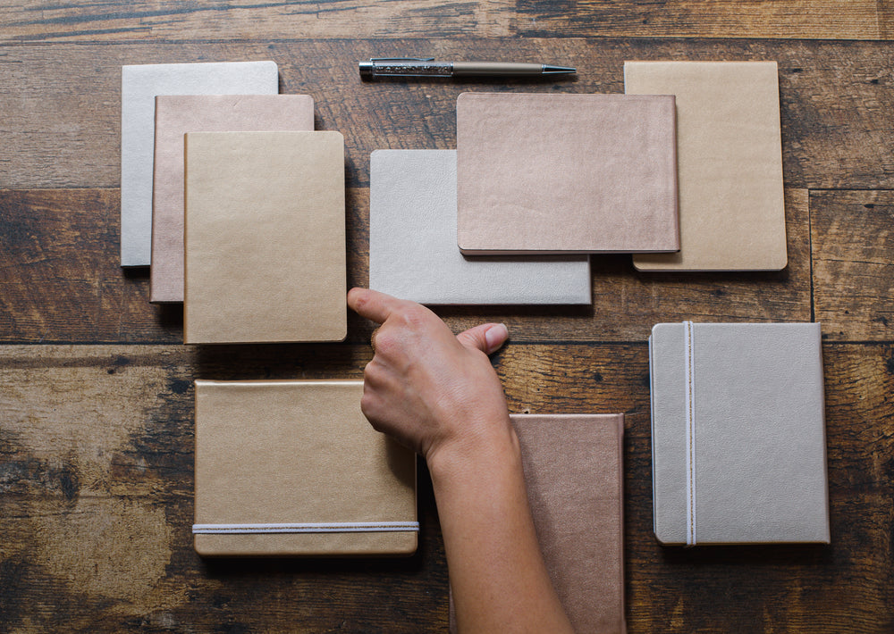 flatlay of notebooks pens and a persons hand