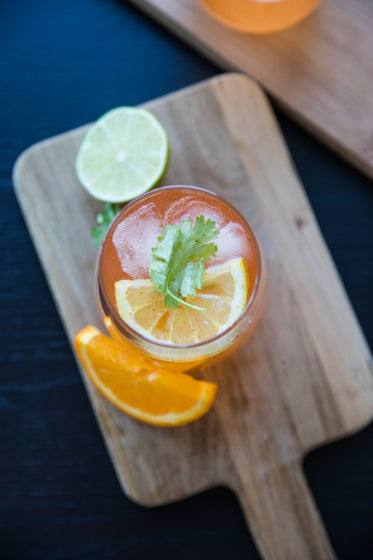 flatlay of orange beverage with lime and orange garnish