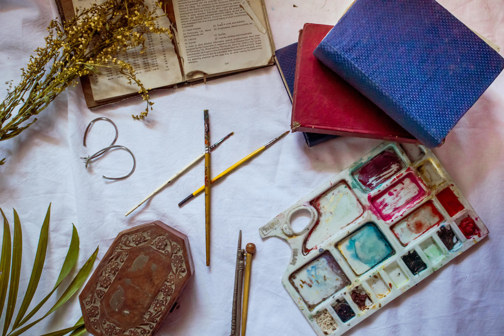 flatlay of painting supplies and books with dried flowers