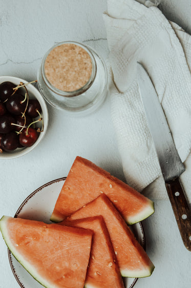 flatlay of sliced watermelon  a knife and cherries