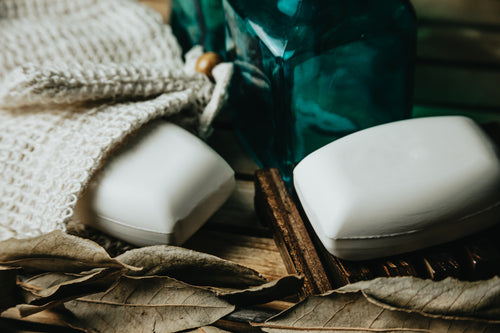 flatlay of two bars of white soap and dried leaves