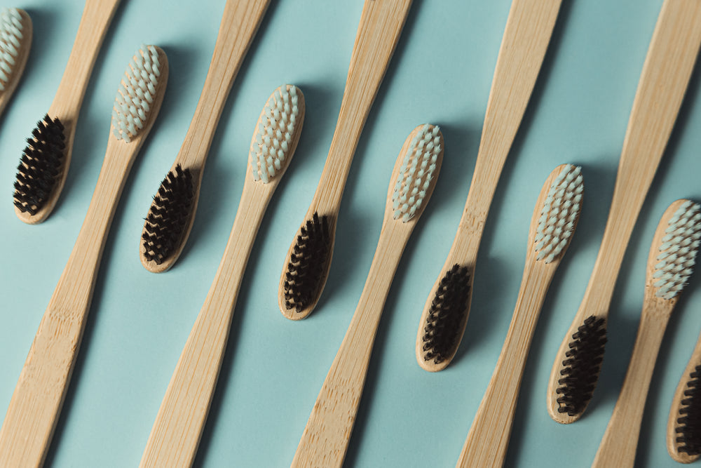 flatlay of wooden toothbrushes laying bristles up on blue