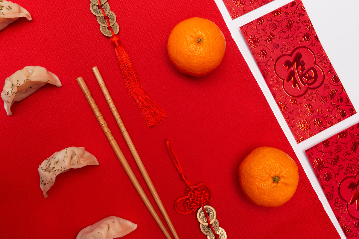 flatlay with dumplings and chopsticks against a red background