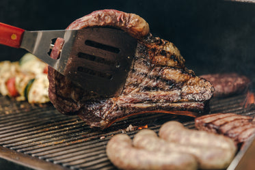 flipping a big steak on a grill